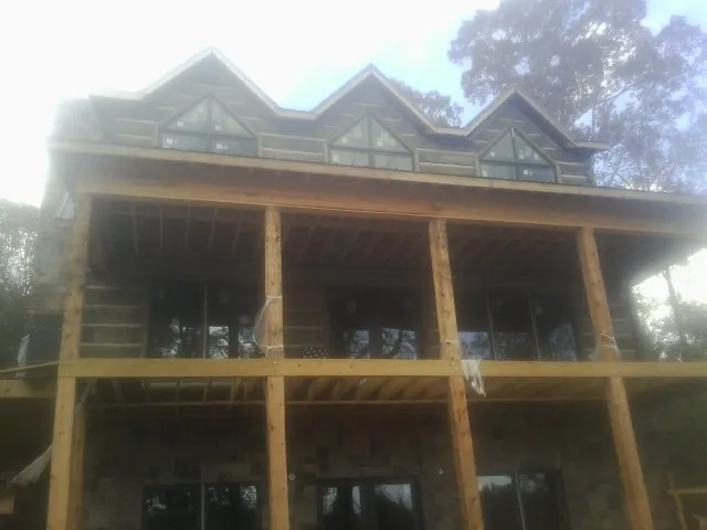 Dormers and porch framing on a large log home under construction — Roof Coating work by our crew in Yanceyville