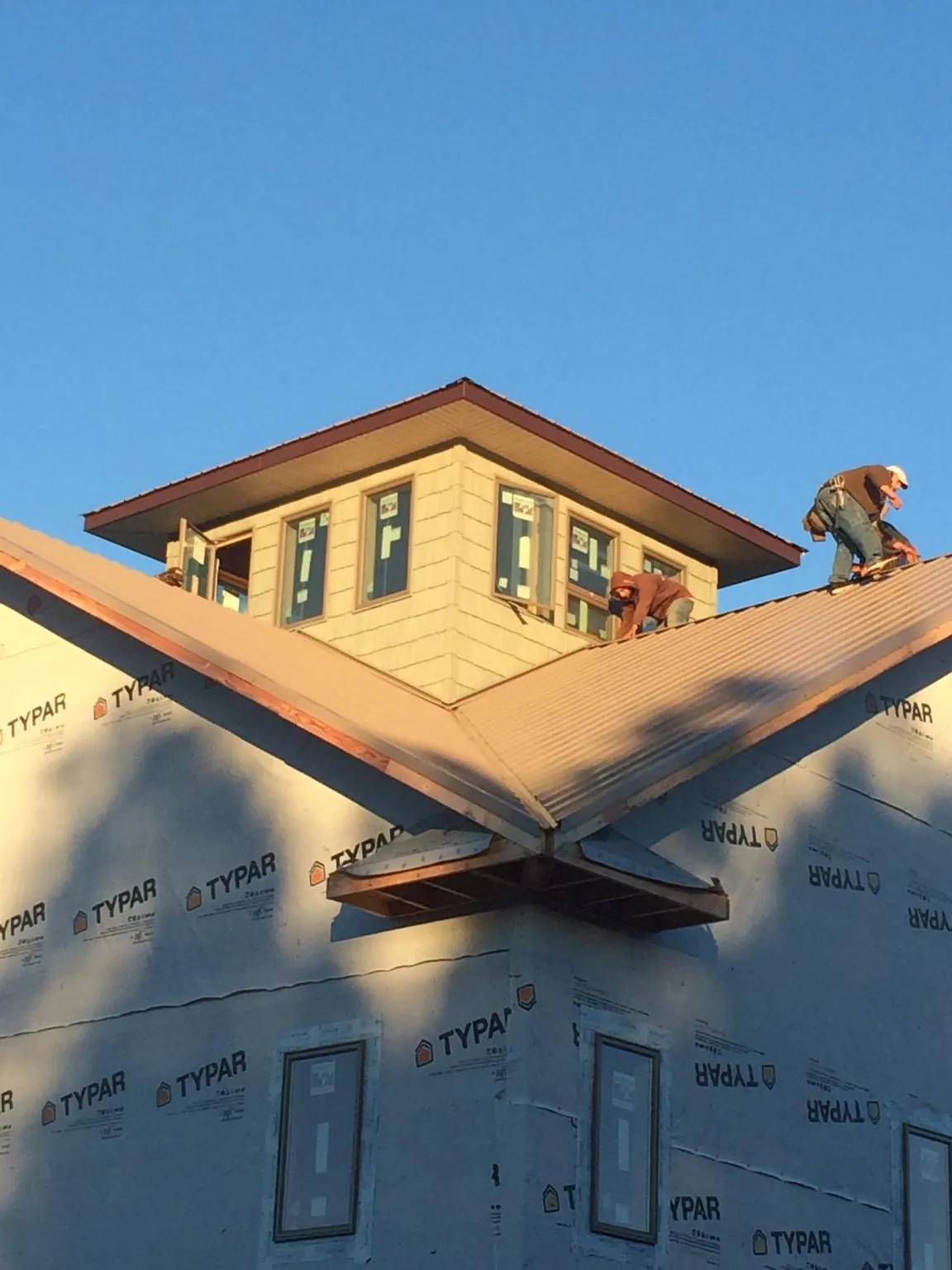 Roofers working around a rooftop cupola on a new metal roof at sunset — Roof Waterproofing in Yanceyville by Roofing Brothers